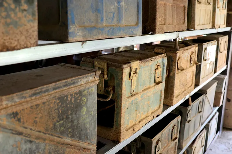 Old metal ammunition cans stacked on storage shelves